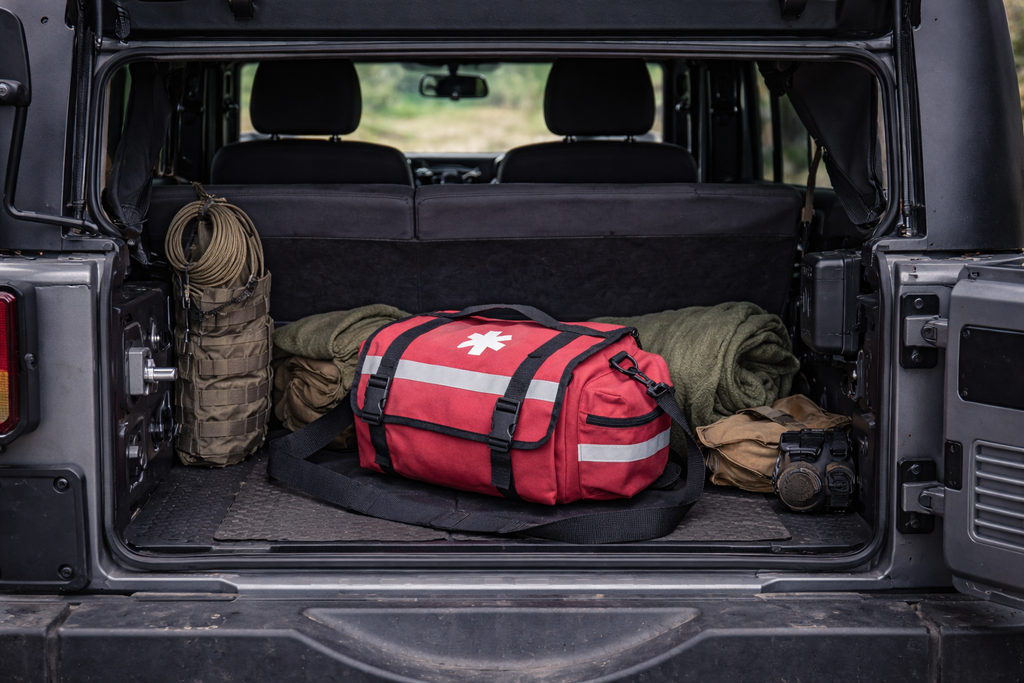 Red emergency bag in the back of a vehicle with rolled-up mats.