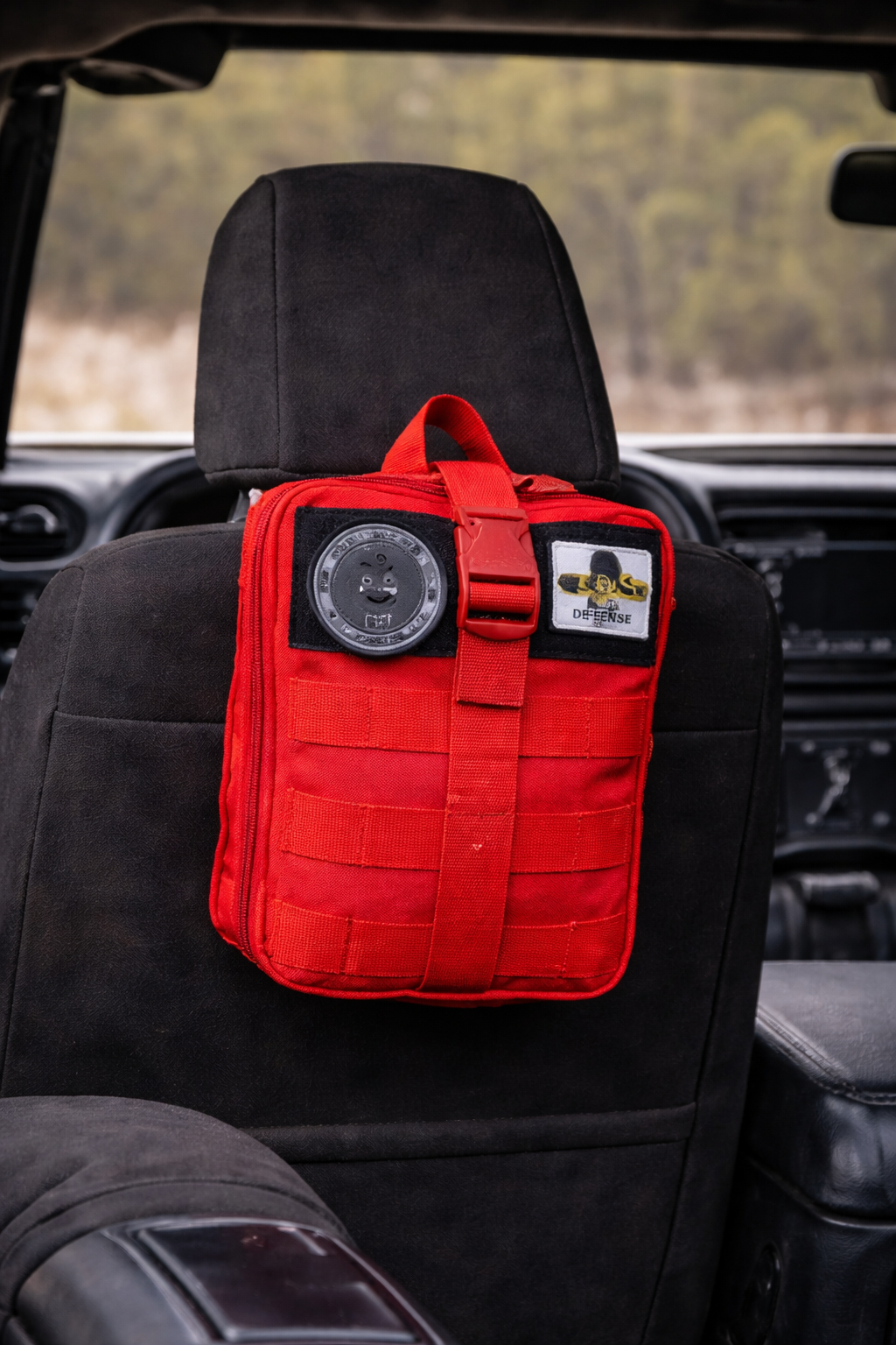 Red tactical pouch on a car seat with a blurred outdoor background
