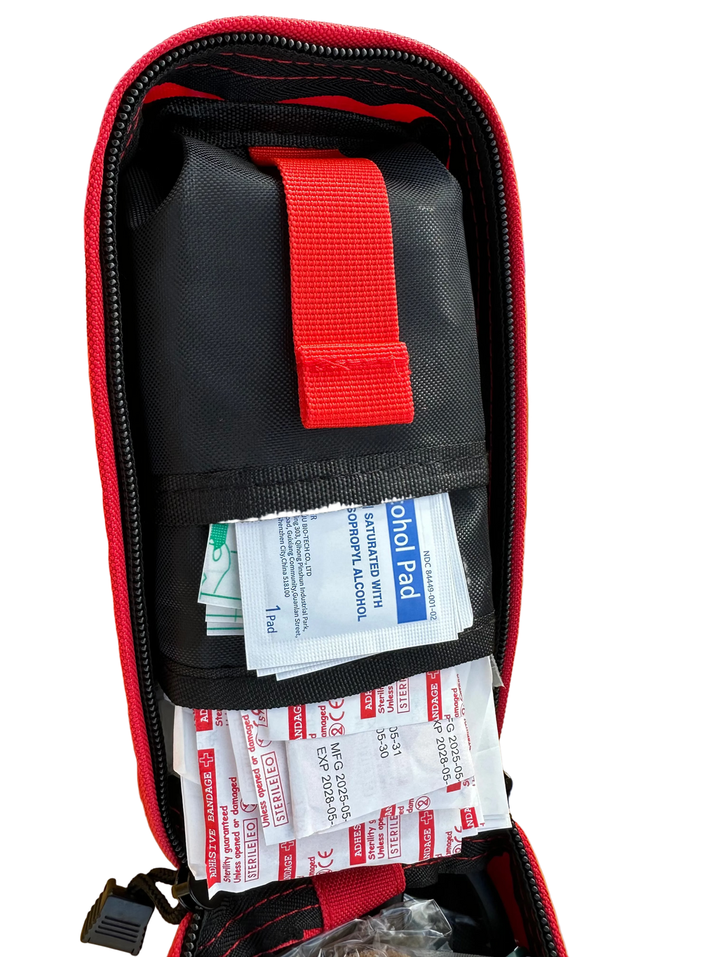 First aid kit with bandages in a red and black case on a yellow surface