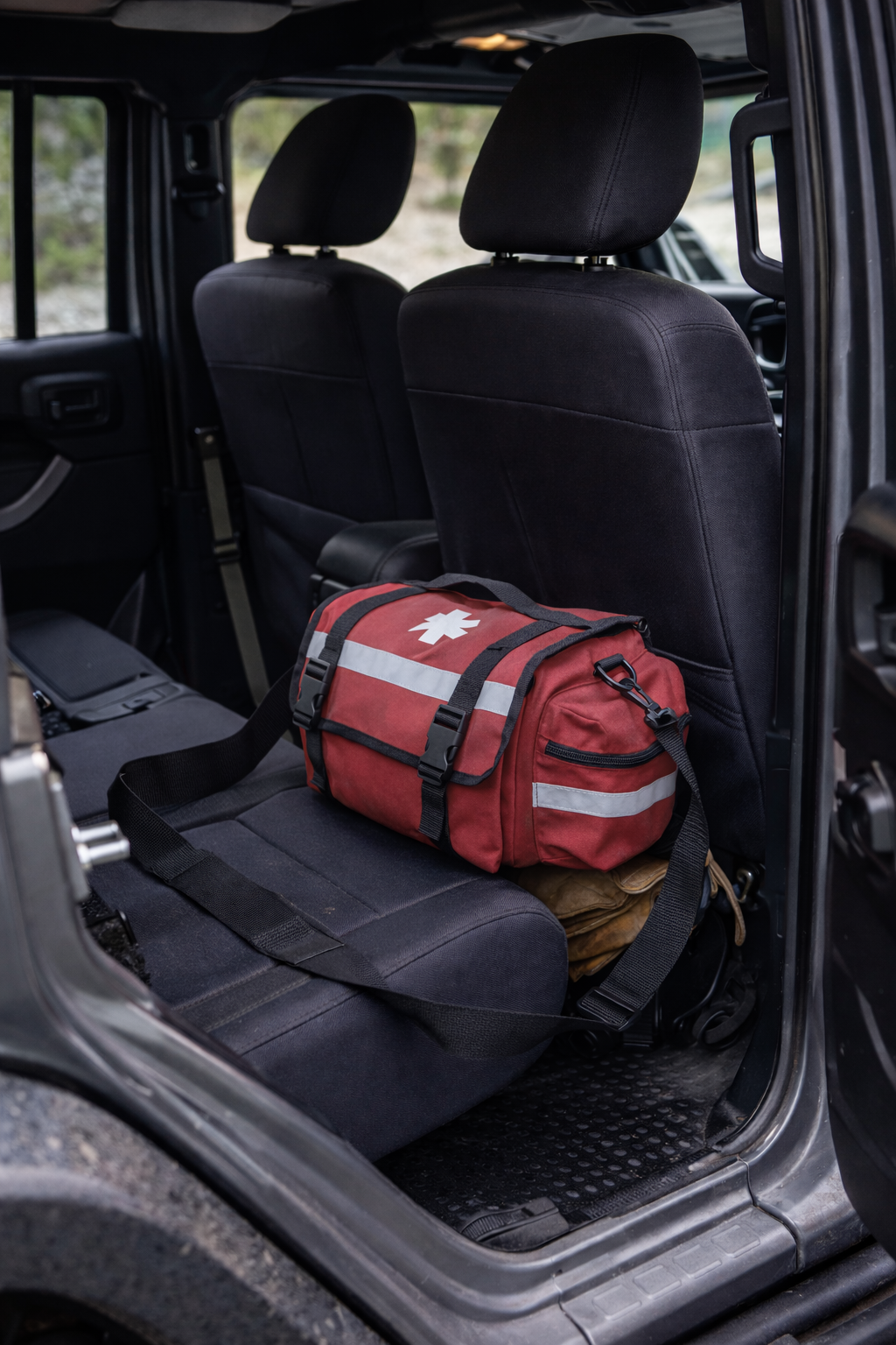 Red emergency bag with reflective stripes on a car seat inside a vehicle